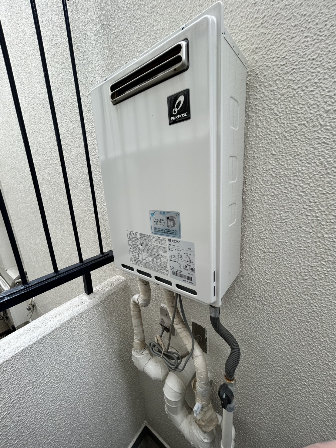 給湯器。交換前の旧型ガス給湯器。配管も経年した状態の設置まわり（神戸市東灘区・施工前）
