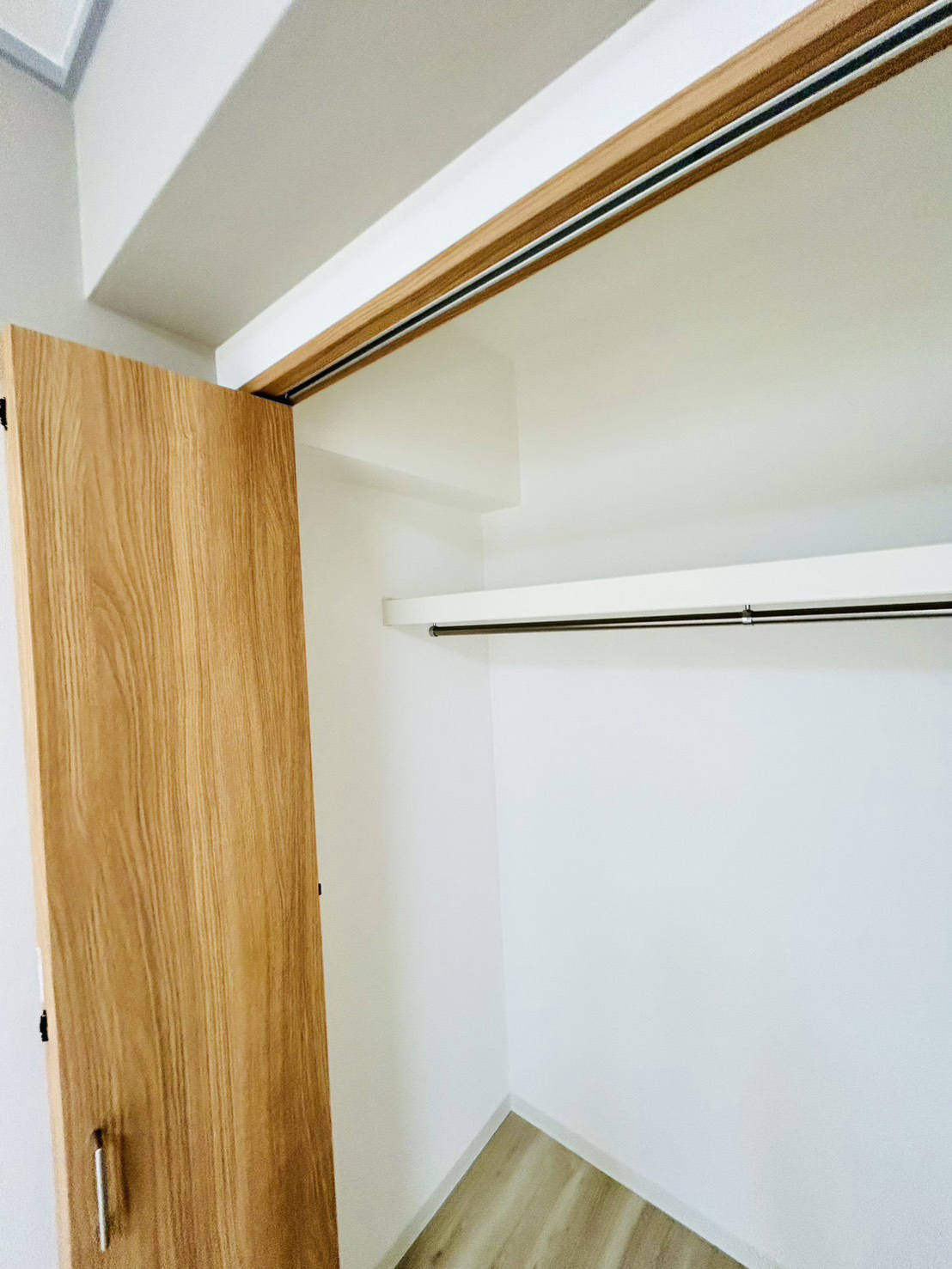 洋室の収納。ハンガーパイプと枕棚を備えた、扉を開けたクローゼットの内部（神戸市東灘区・施工後）