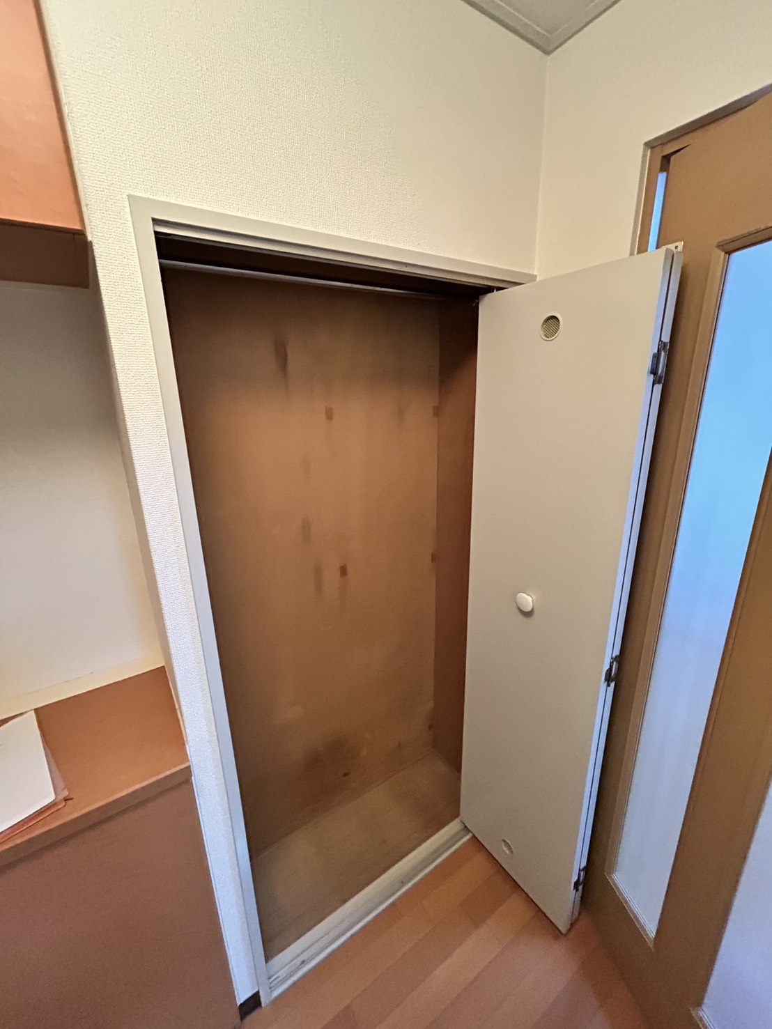 玄関収納。扉を開けた内部が茶色い木目のままになっている、改装前の収納（神戸市東灘区・施工前）