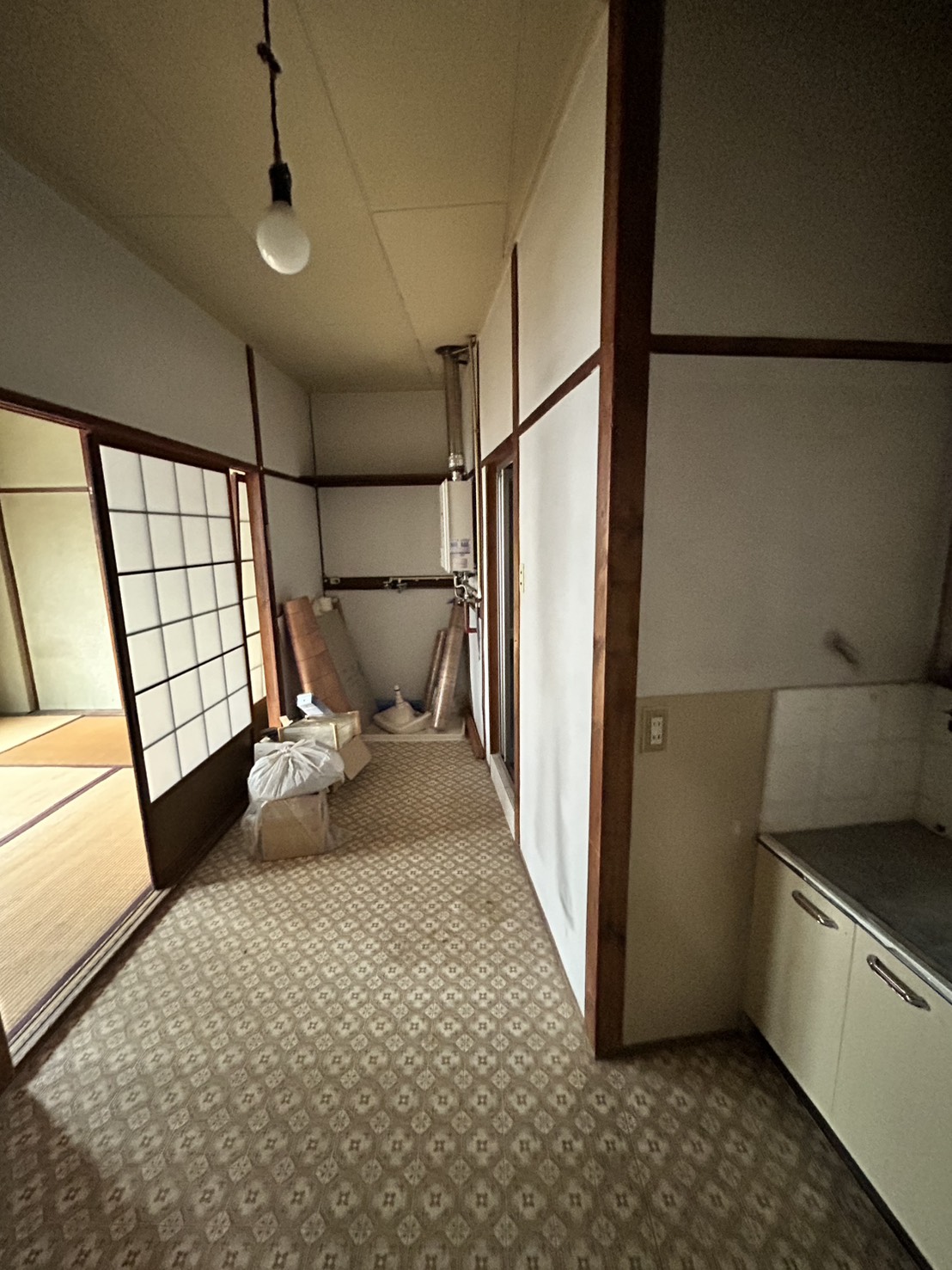 改装前のダイニングキッチン。古い柄物クッションフロアと旧式の給湯器が残る空き家の状態（大阪市西区）