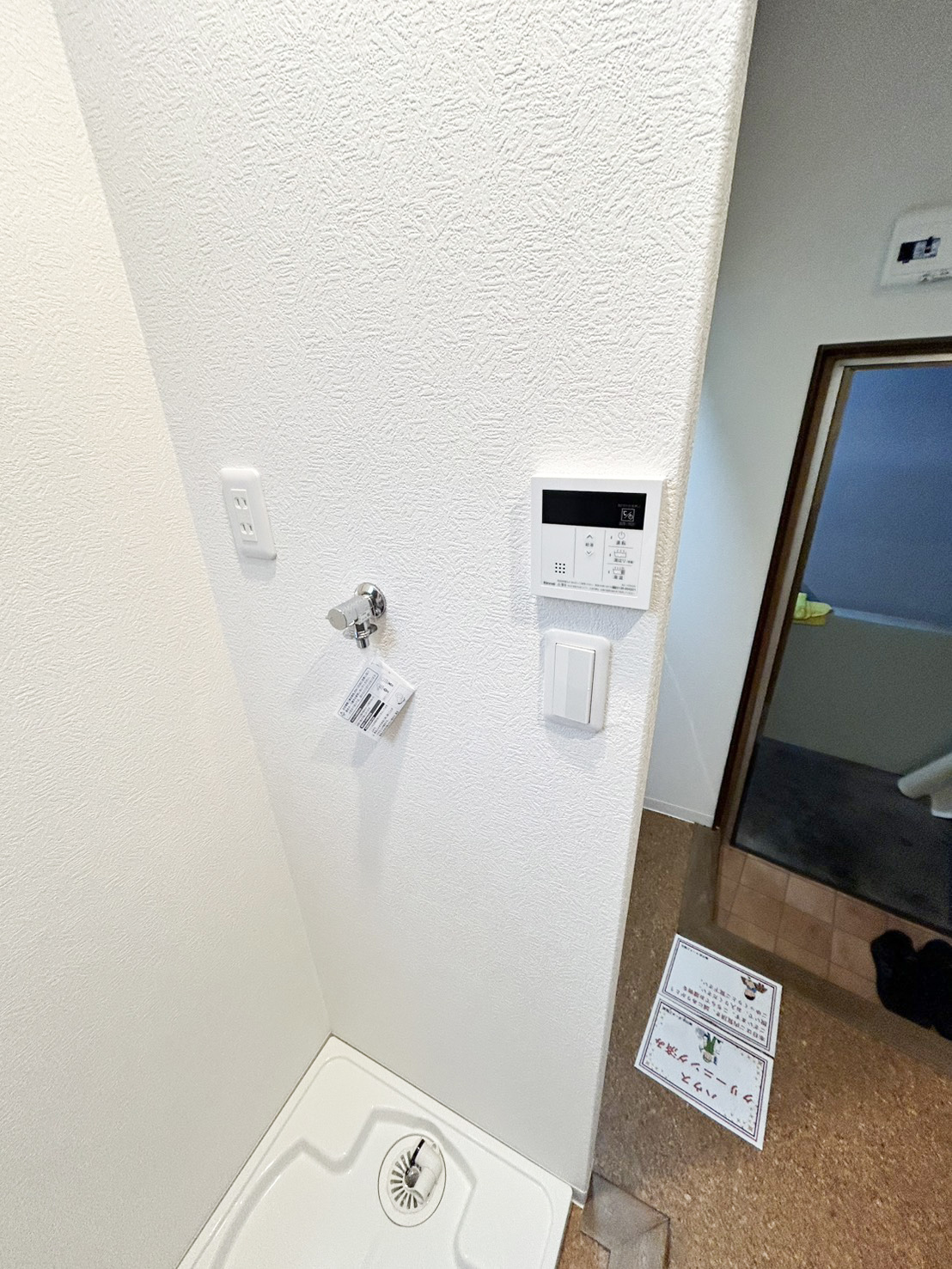 洗濯機置き場と給湯リモコンまわり。すっきり整えた白い水まわりの壁（大阪市西区・施工後）