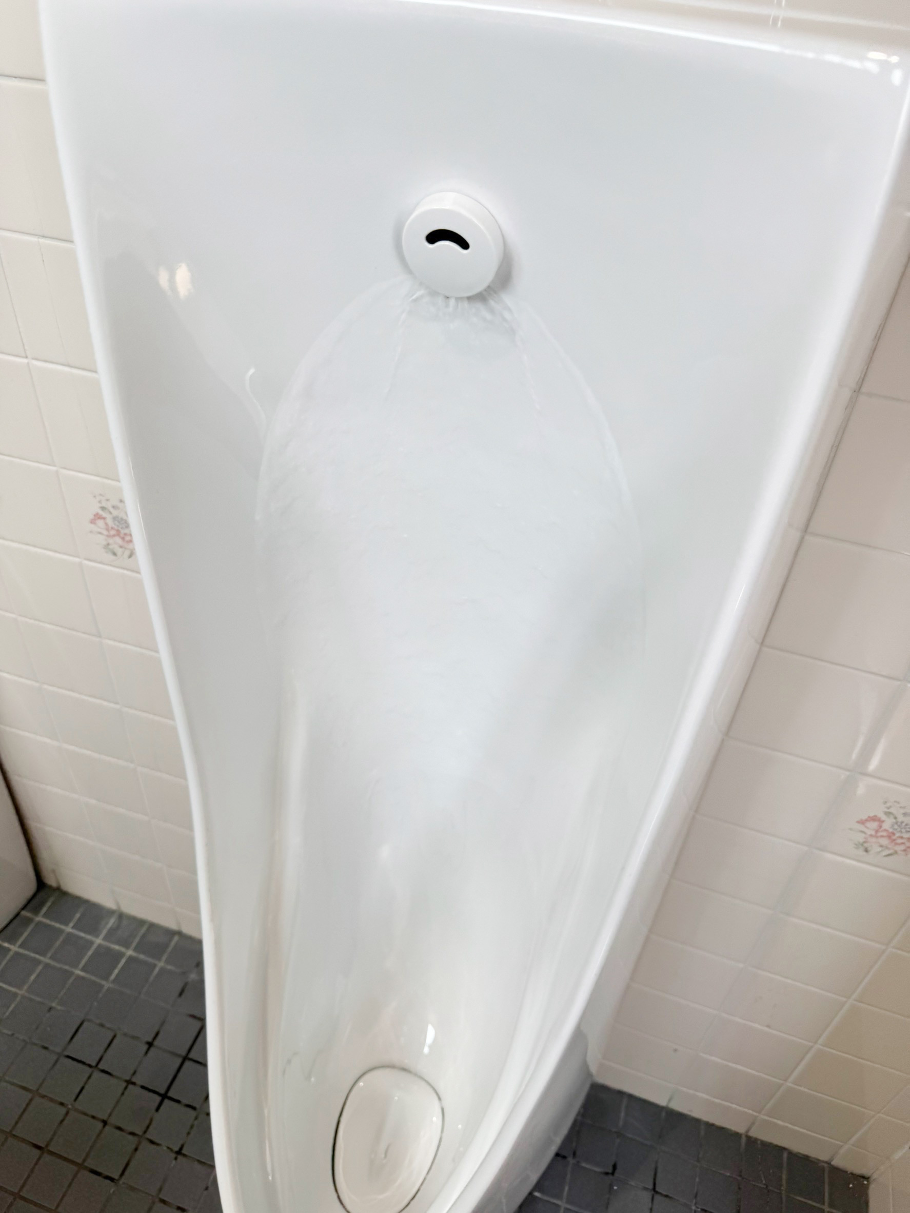 交換後の小便器の通水確認。センサーが反応し、洗浄水が便器全体を流れる様子（神戸市東灘区・施工後）